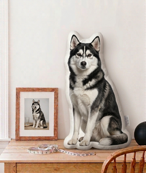Husky-shaped pillow on a wooden table with a framed photo and cat in the background